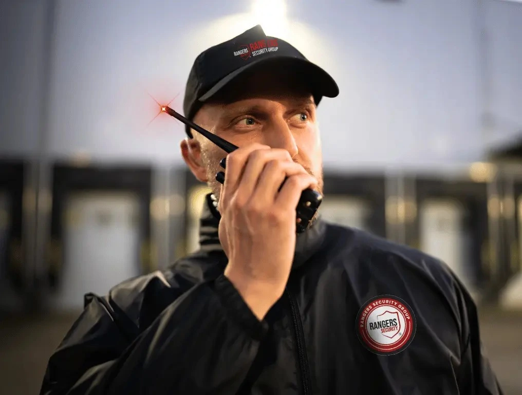 Rangers Security Group’s security guard in uniform, using a wireless device to communicate with the team while providing proactive on-site security.
